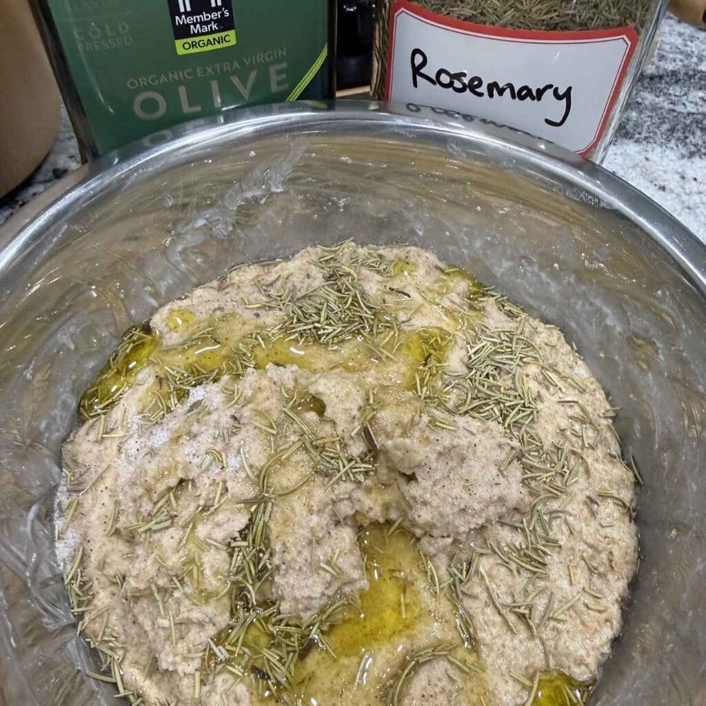 Adding in the sourdough starter, salt, rosemary and the olive oil